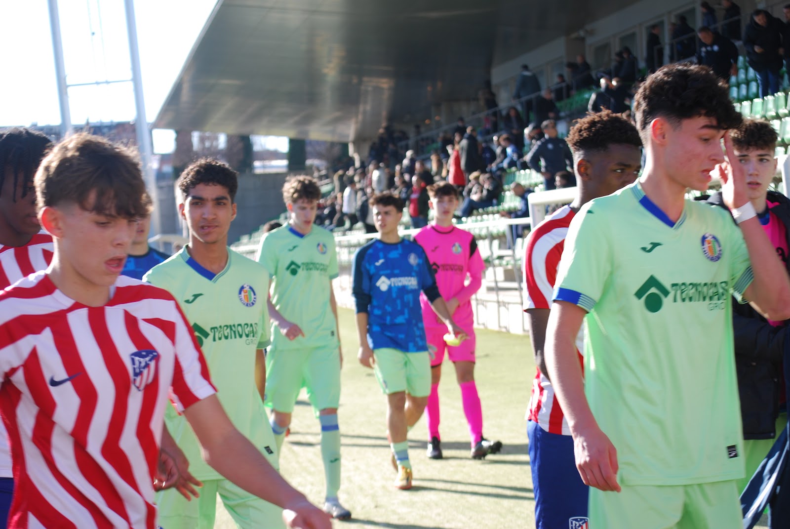 Jugadores y árbitros junto a la tribuna de Las Rozas